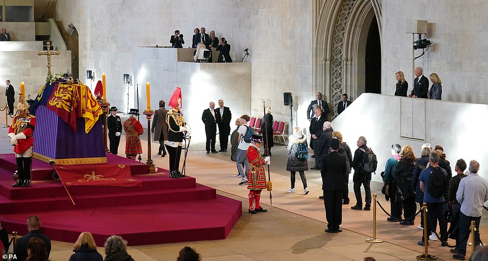 The Bidens stood from a balcony to view the Queen's coffin inside Westminster Hall Sunday as mourners stood in line to walk by and pay their respects to the late monarch