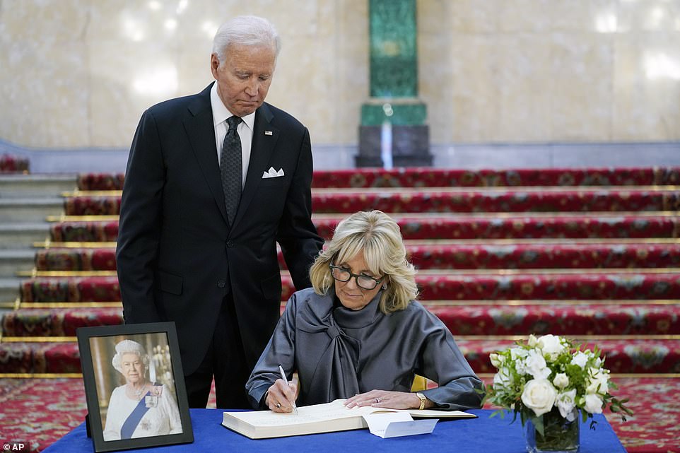 Jill signs a book of condolence as President Biden stands over her shoulder