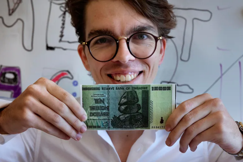 Eric Martinez, a graduate student in the Department of Brain and Cognitive Science at the Massachusetts Institute of Technology, holds a Zimbabwean $10 trillion bill, Friday, Sept. 9, 2022, 