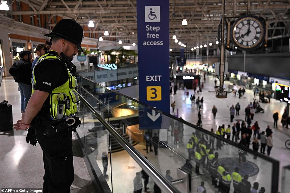 A police officer observes a national moment of reflection at Waterloo Station in London ahead of the Queen's funeral tomorrow