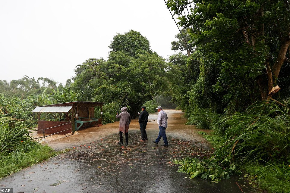 People look at a flooded road during the passing of Hurricane Fiona through Cayey, Puerto Rico on Sunday