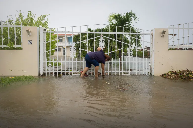 A man stands at a gate with water up to his mid-shins.