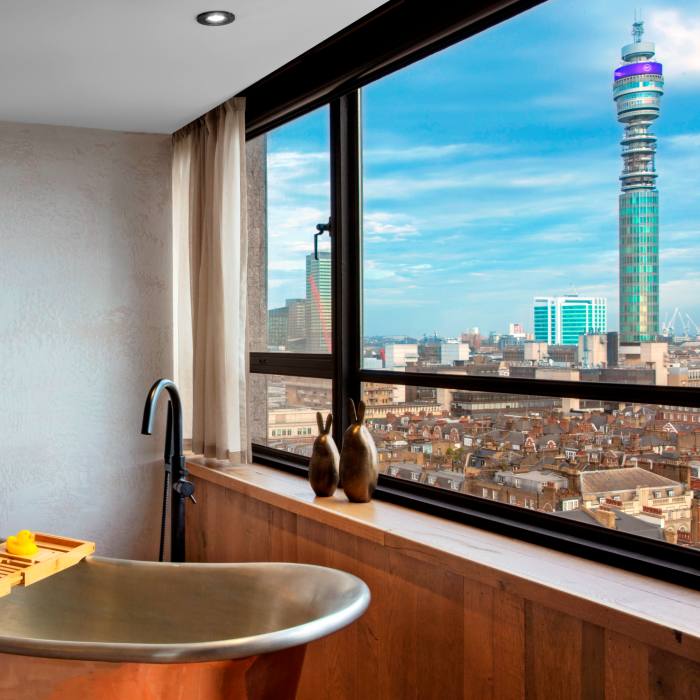 A silver bathtub in a room at the Treehouse, looking over London’s BT Tower