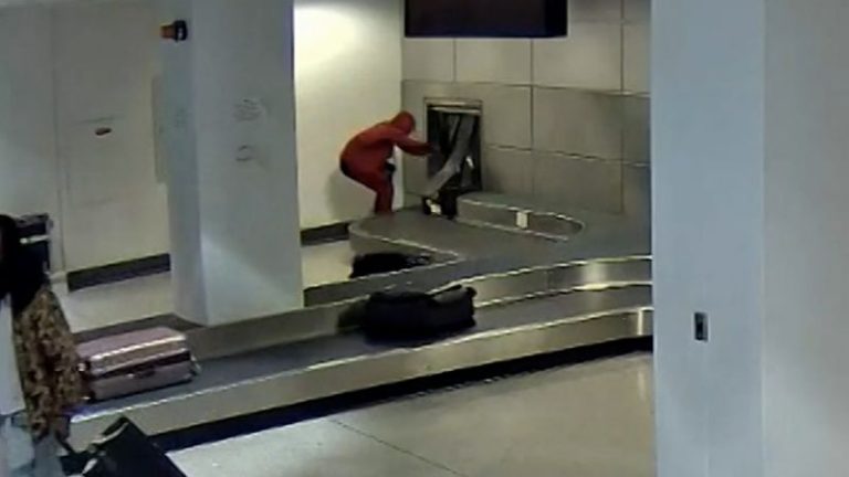 Surveillance video shows man crawling through luggage carousel at airport