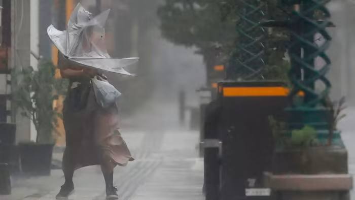 A woman struggles against strong wind and rain in Miyazaki after the typhoon pounded southern Japan 