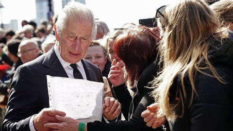 King Charles reacts as a member of the public hands him a drawing of his late mother, as he meets with people waiting in line to pay respects at the Queen's lying in state on September 17, 2022.