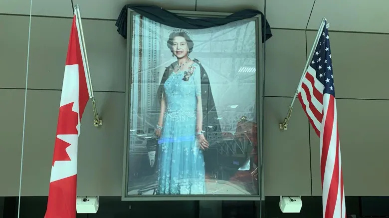 A photograph of Queen Elizabeth II hangs in the North Bay Memorial Gardens, next to Canadian and American flags. 