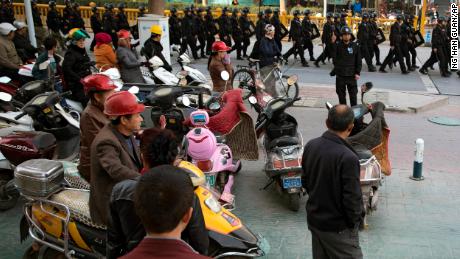 Residents watch a convoy of security personnel armed with batons and shields patrolling through Kashgar, Xinjiang, on November 5, 2017.