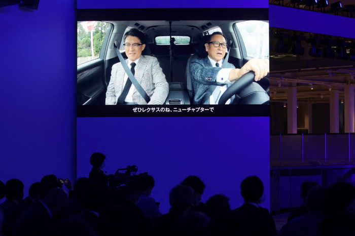 Toyota president Akio Toyoda is seen on a screen during a briefing on EV battery strategies at the company’s showroom in Tokyo