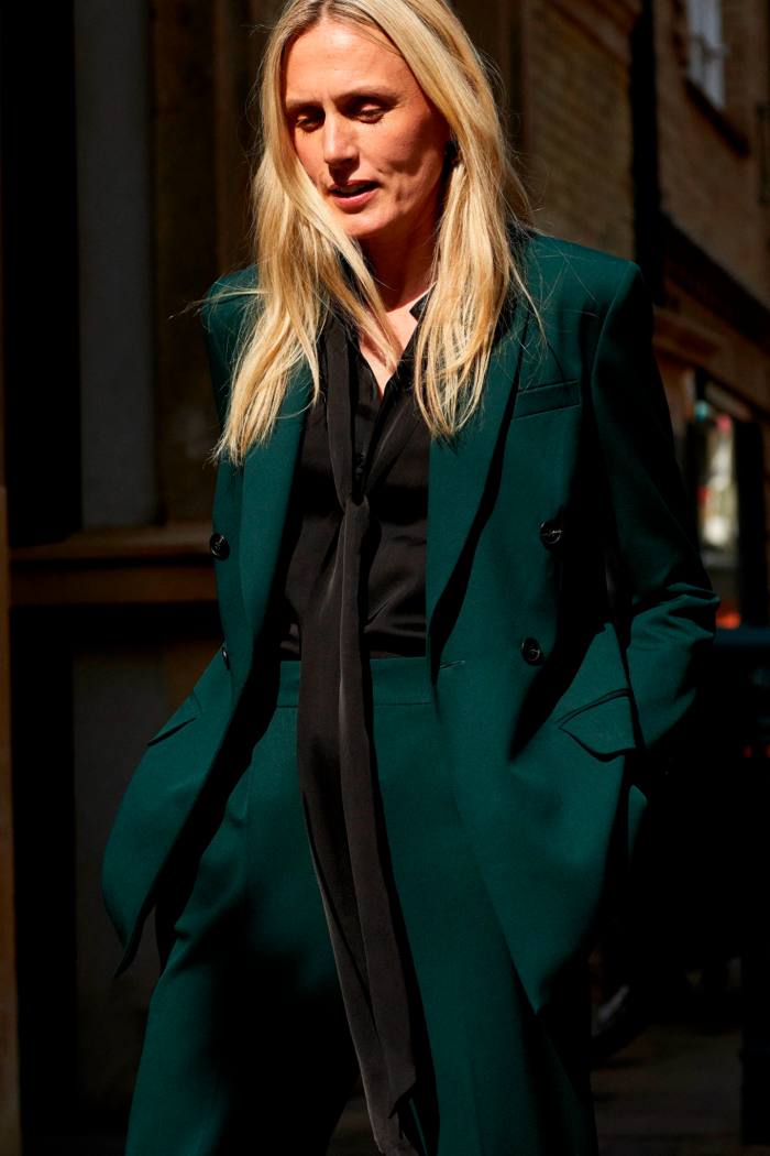 A woman models a blazer in bottle green