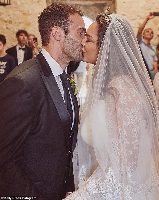 Intimate: Another snap showed the two kissing after saying their vows at the end of the aisle as they are watched on by family and friends in the pews