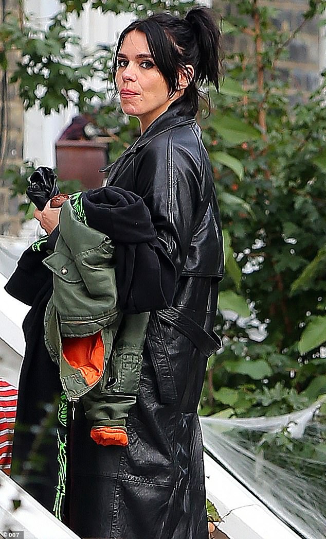 Hot mama: The doting mother-of-two carried her son's khaki jacket and black jumper in her arms