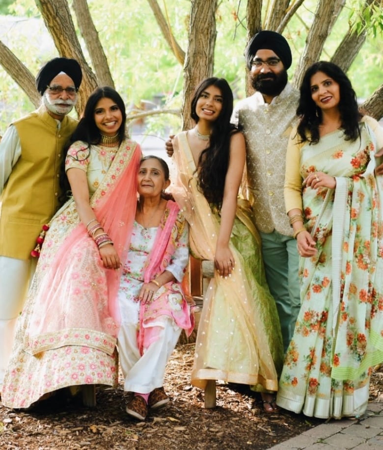 Three generations of a family dressed in traditional Indian clothes pose for the camera. 