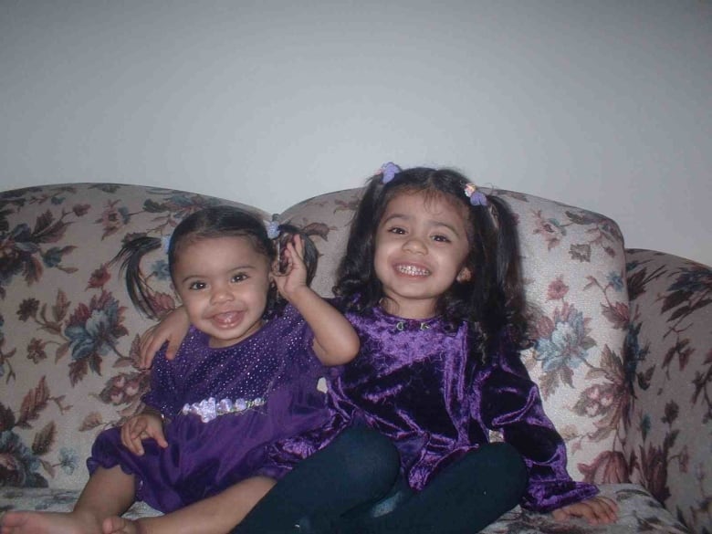 Two girls in matching purple outfits sit together. 