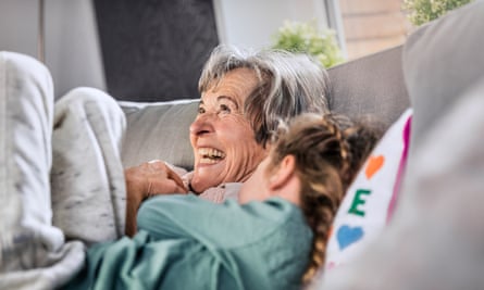 A grandmother lying by granddaughter on sofa at home