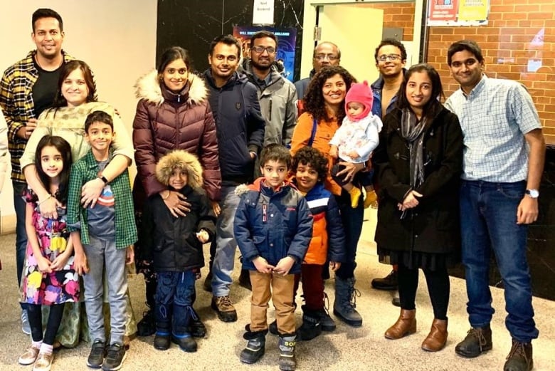 A group of families stand smiling in the lobby of a theatre. 