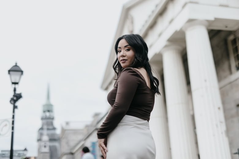 A woman stands in front of a building with columns.