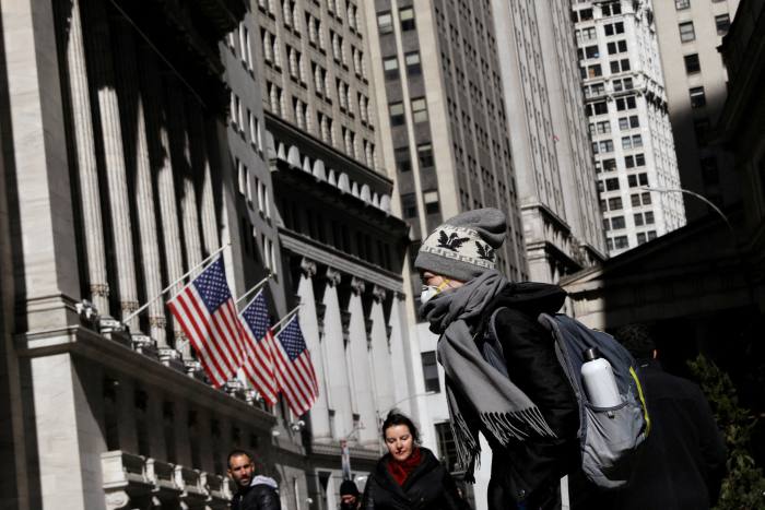 A woman wears a mask near the New York Stock Exchange 