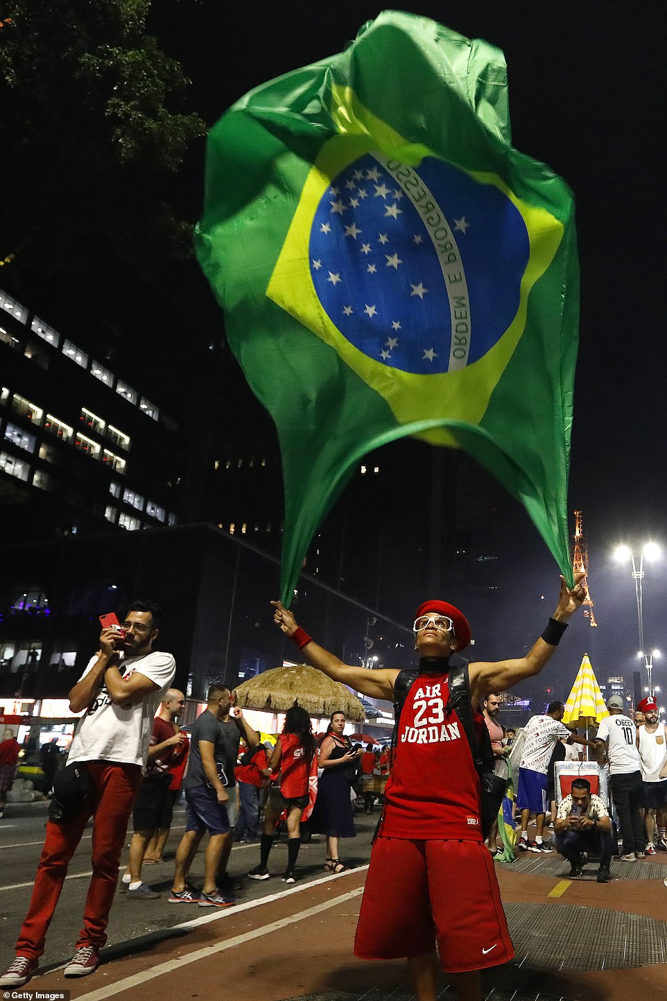 A supporter of the President elect Lula celebrates by waving a giant Brazilian flag on the streets of Sao Paulo