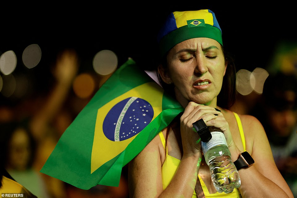 A supporter of Brazil's President and presidential candidate Jair Bolsonaro holds a Brazilian flag, during the Brazilian presidential election run-off, in Brasilia, Brazil