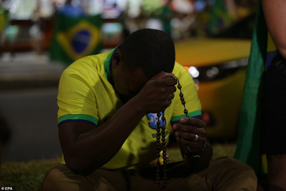 A supporter of Brazilian President and re-election candidate Jair Bolsonaro lowers his head as results come in