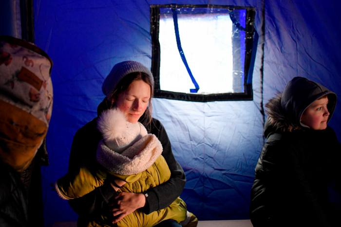  A refugee fleeing the conflict from neighboring Ukraine holds her baby as she sits in a tent at the Romanian-Ukrainian border, in Siret, Romania, in February 