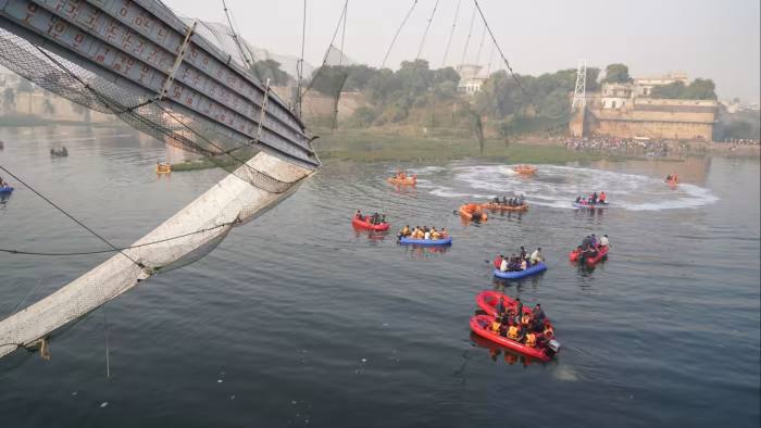 Emergency workers in boats search the waters beneath the collapsed Morbi bridge in Gujarat state 