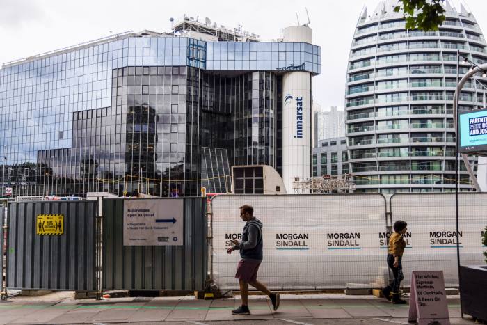 People walking by a big glass building