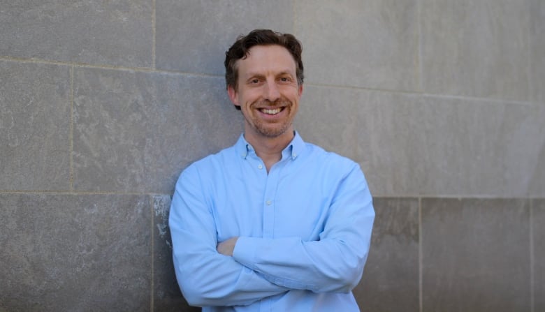 Jonathon Penney, a law professor whose research focuses on internet, society and data policy at York University’s Osgoode Hall Law School, stands in front of a stone brick wall.  