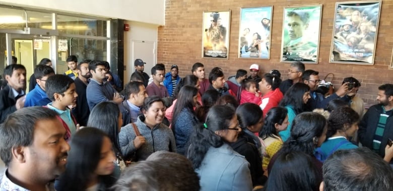 A large group of people pack into the lobby of a theatre.