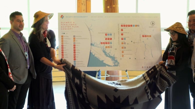 A map showing the potential sites for the 2030 Olympics and Paralympics in the Whistler, B.C. region is unveiled from behind a decorated blanket.