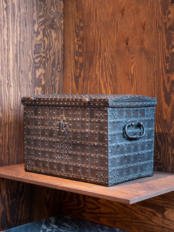 A 17th-century box-chest with metal rivets in neat rows all along the facia