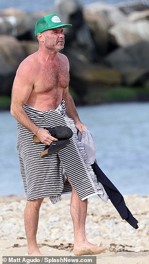 He put on a green trucker cap and retrieved his shirt and clogs from the sand