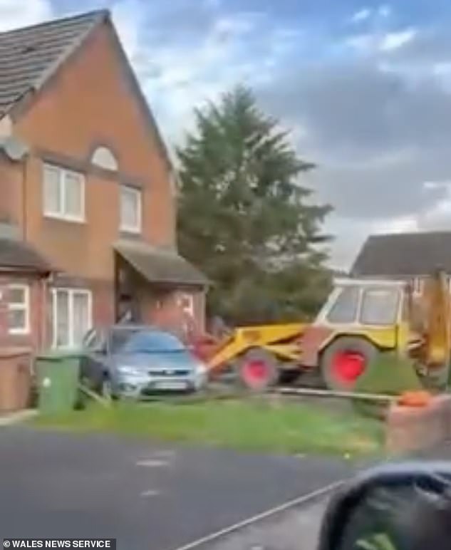 Neighbours watched in shock as the digger backed up before lurching forwards towards the house in Blackwood, South Wales on Tuesday, and hitting its porch