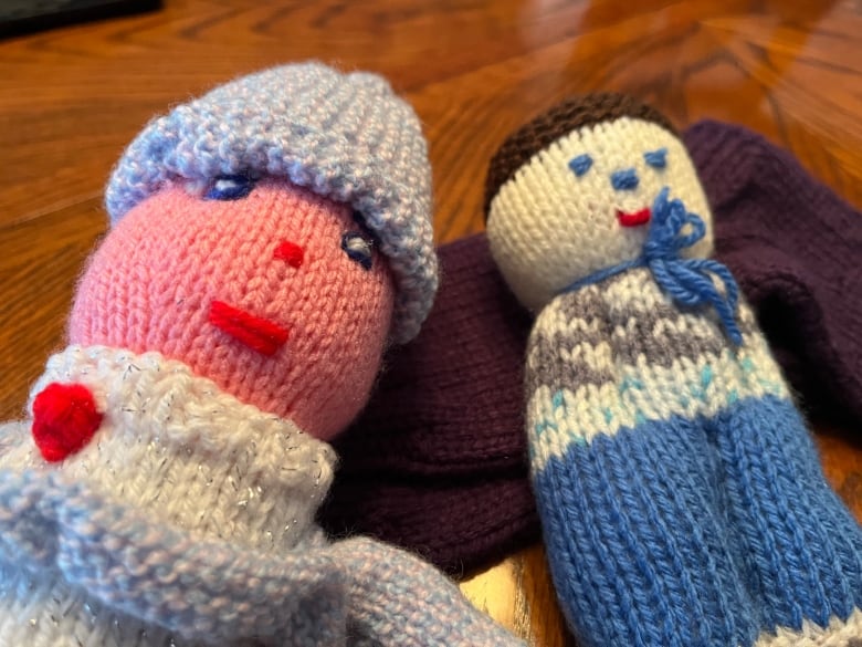 A close-up photo of two knitted dolls on a table.