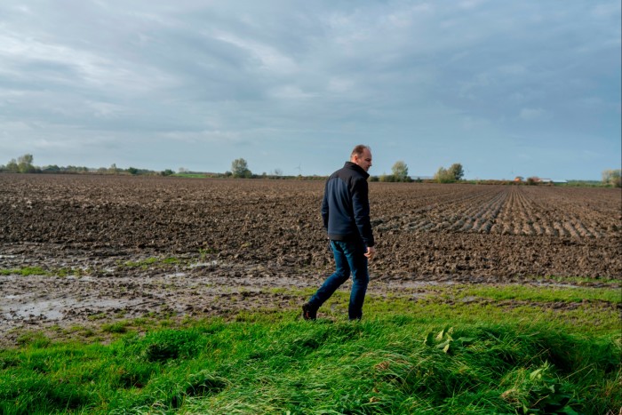 Hendrik Jan ten Cate walks along a grassy area bordering a ploughed field