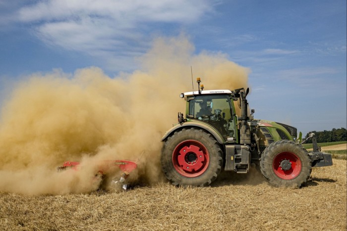 A tractor moves in a cloud of dust as it harrows a field