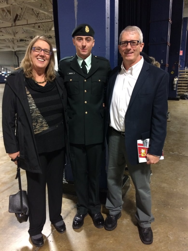 A Canadian soldier in dress uniform stands between a man and a woman in civilian clothes. 