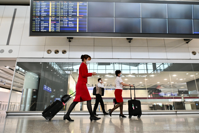 Cathay Pacific staff walk through the arrival hall at Hong Kong International Airport