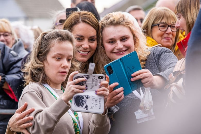 A person poses for a selfie with two other people.