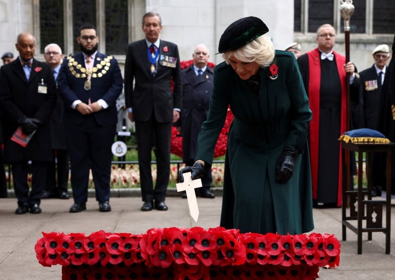 A person places a small cross in a display of poppies.