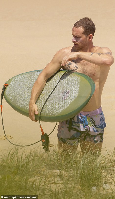 He glanced down at his surfboard while walking up the beach