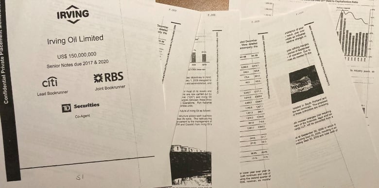 A series of six pages of a report are overlaid on one another, sitting atop a wooden desk. 