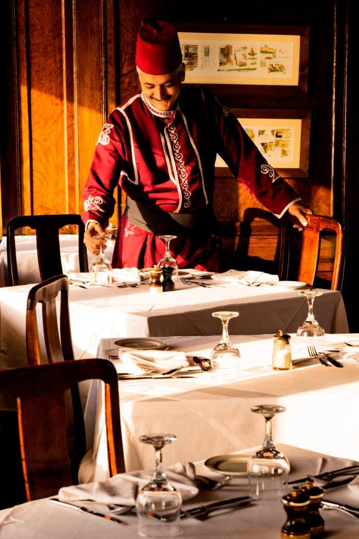 Waiter dressed in red sets tables