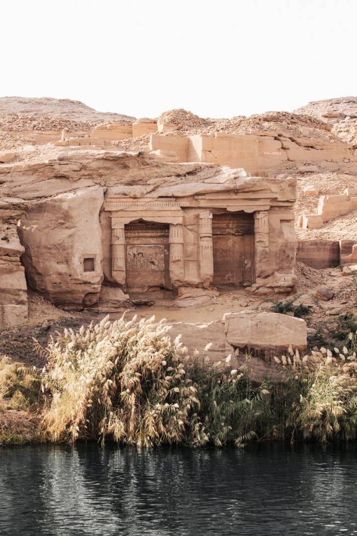 Two doorways carved in rock along a river