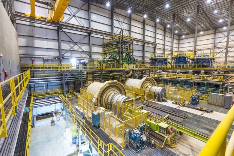 Yellow, round machines are inside of a large factory.