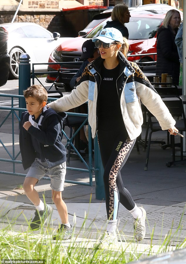 She showed off her slender figure in black leggings with leopard print trim, a black T-shirt and a white puffer jacket with more leopard print detail