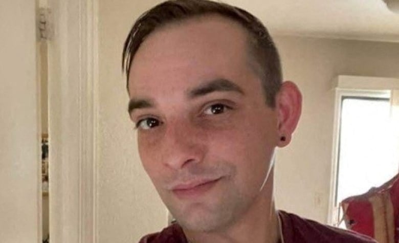 A man with short hair and an earring smiles for the camera.