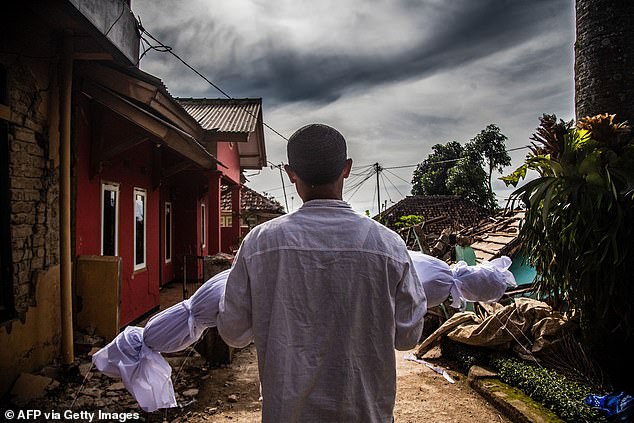 A villager carries the body of his dead son following a 5.6-magnitude earthquake in Cianjur on Tuesday