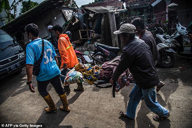 Villagers carry an injured victim following the earthquake in Cianjur on Tuesday. At least 900 were hurt in the quake